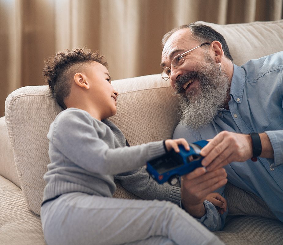 Grandfather and grandson on couch smiling